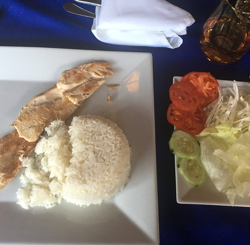 chicken and rice on a plate with a salad of lettuce, tomatoes and cucumbers on the side