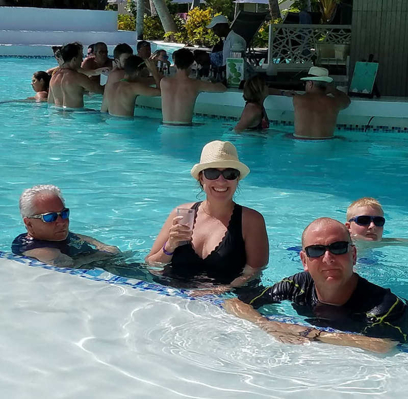 Shane and her husband, dad, and son in the pool with a swim up bar in the background
