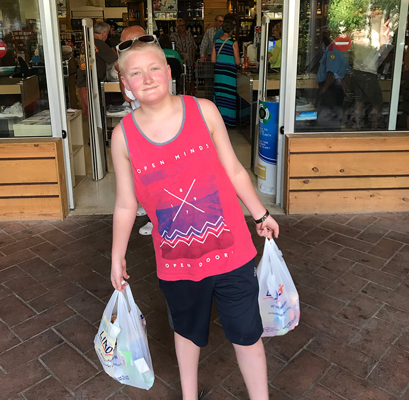 Teen boy carrying plastic bags of groceries out of the super market